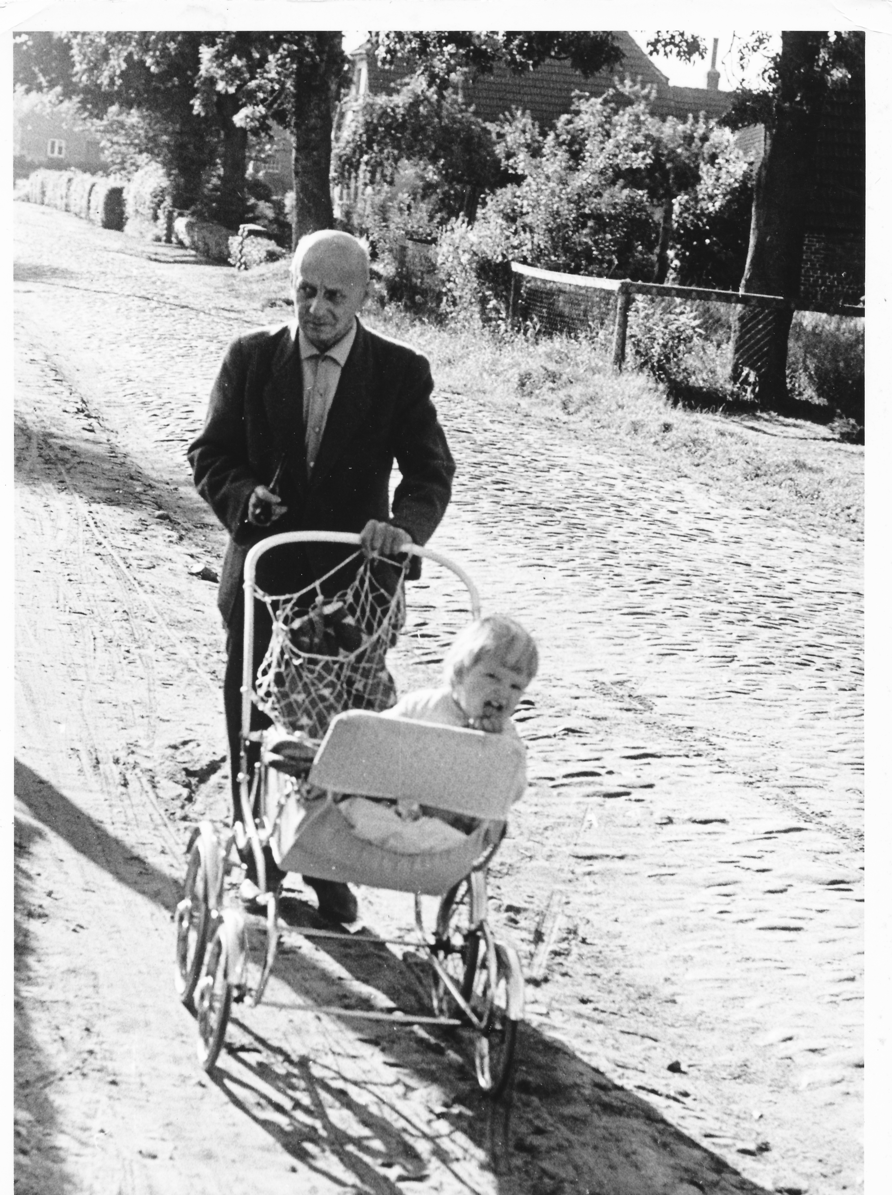 Historisches Foto: Mann mit Kinderwagen auf Kopfsteinpflaster